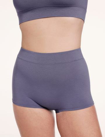On a white studio backdrop, Sonnie wears the Cloud Cotton Boyshort in Slate, shown from the front with a high-rise waistband and soft, smooth cotton modal fabric. sizing: Sonnie wears size Large