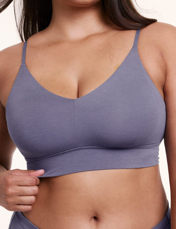 On a white studio backdrop, Alana wears the Cloud Cotton Triangle Bralette in Slate, shown close-up with a V neckline, thin straps, and a smooth underband.