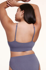 On a white studio backdrop, Alana wears the Cloud Cotton Triangle Bralette in Slate, shown from the back with thin adjustable straps and a wide, soft underband.