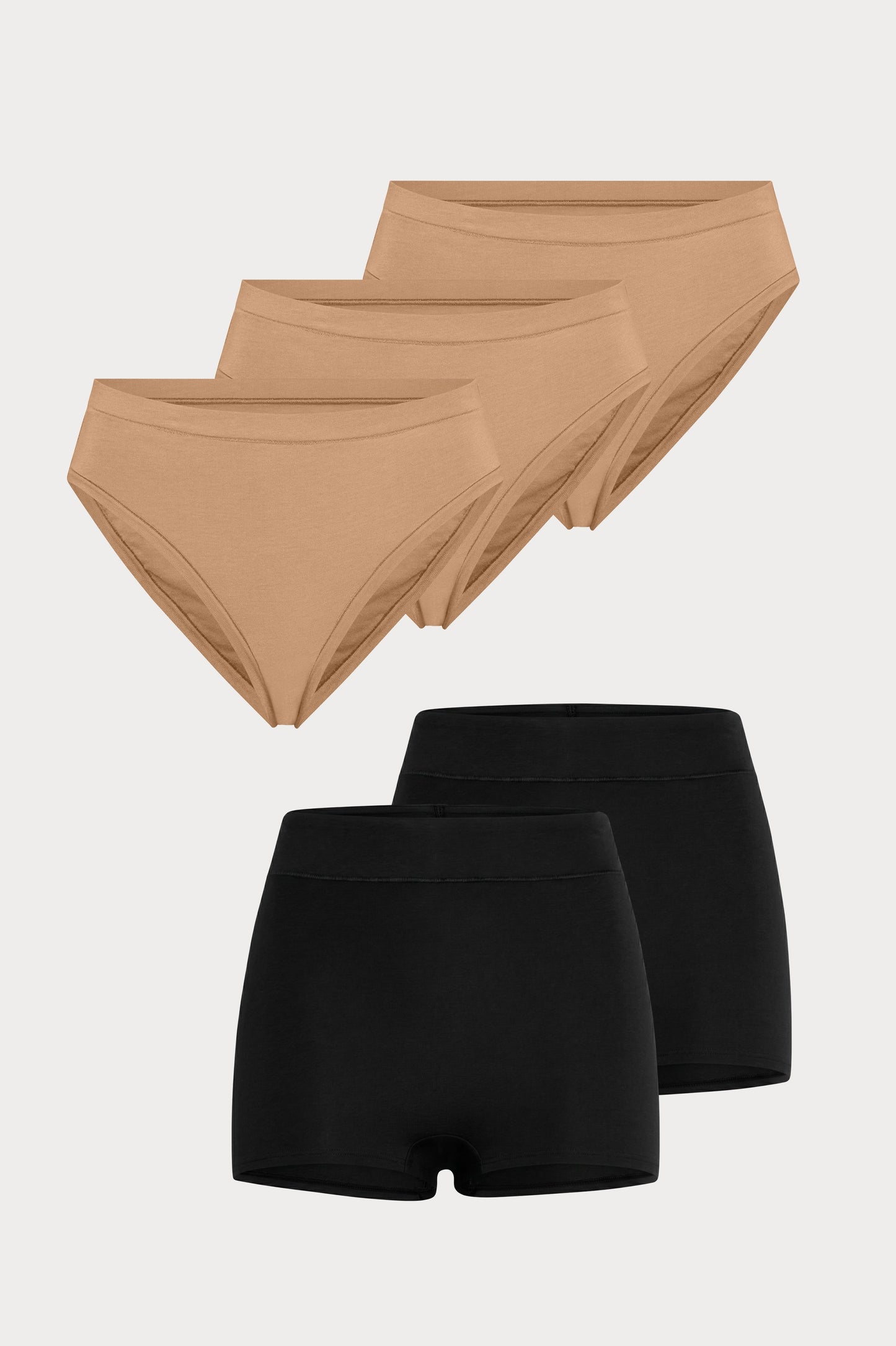 Flat lay image of 3 pairs of the Cloud Cotton French Cut Briefs in Dune next to 2 pairs of the Cloud Cotton Highwaist Boyshort in Black.