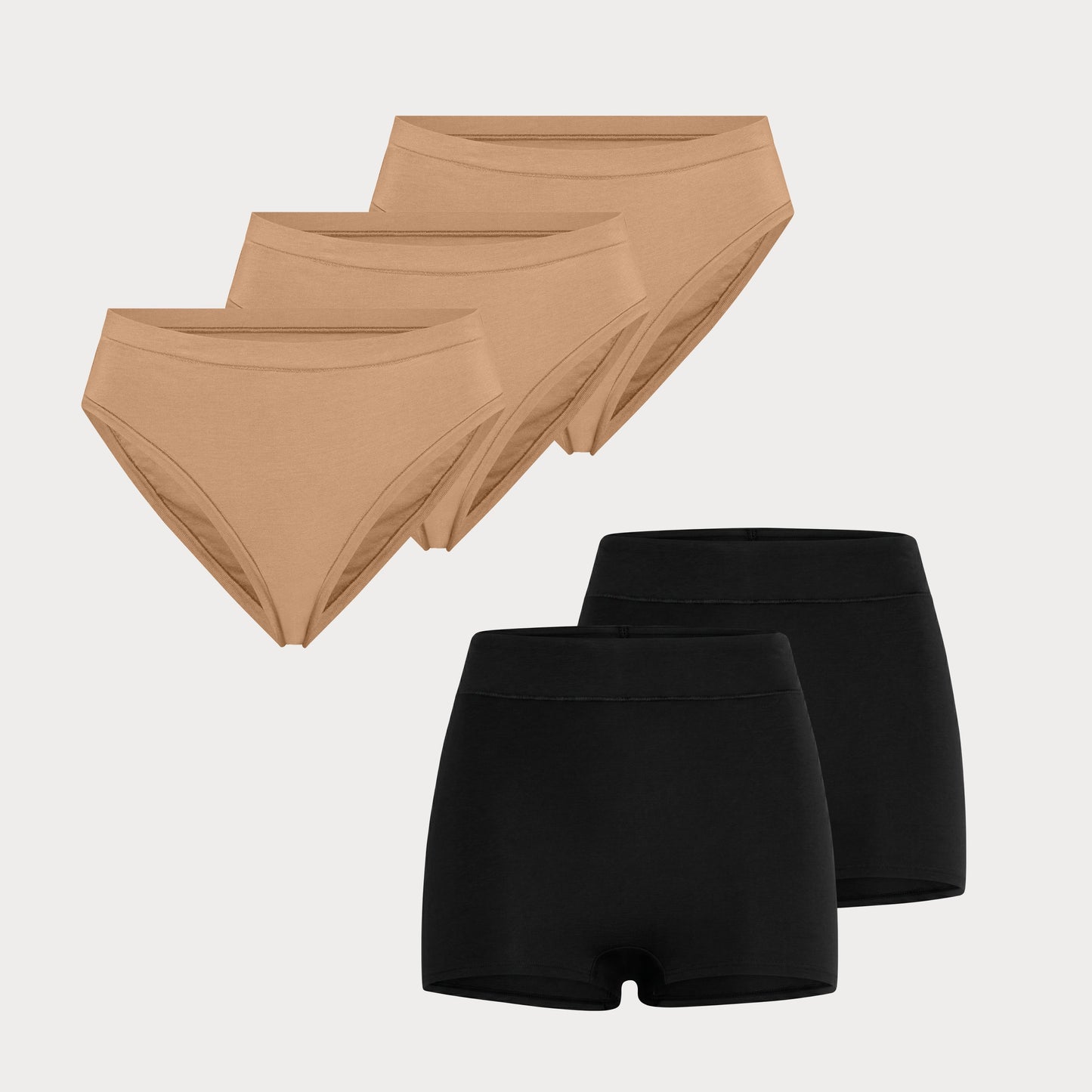 Flat lay image of 3 pairs of the Cloud Cotton French Cut Briefs in Dune next to 2 pairs of the Cloud Cotton Highwaist Boyshort in Black.