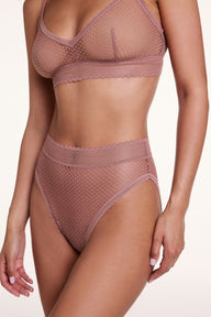 On a white studio backdrop, Courtney wears the Dot Lace Highwaist in Plum with the matching Dot Lace Triangle Bralette in Plum, showing the sheer dot lace fabric, scalloped trim, and high-rise design.