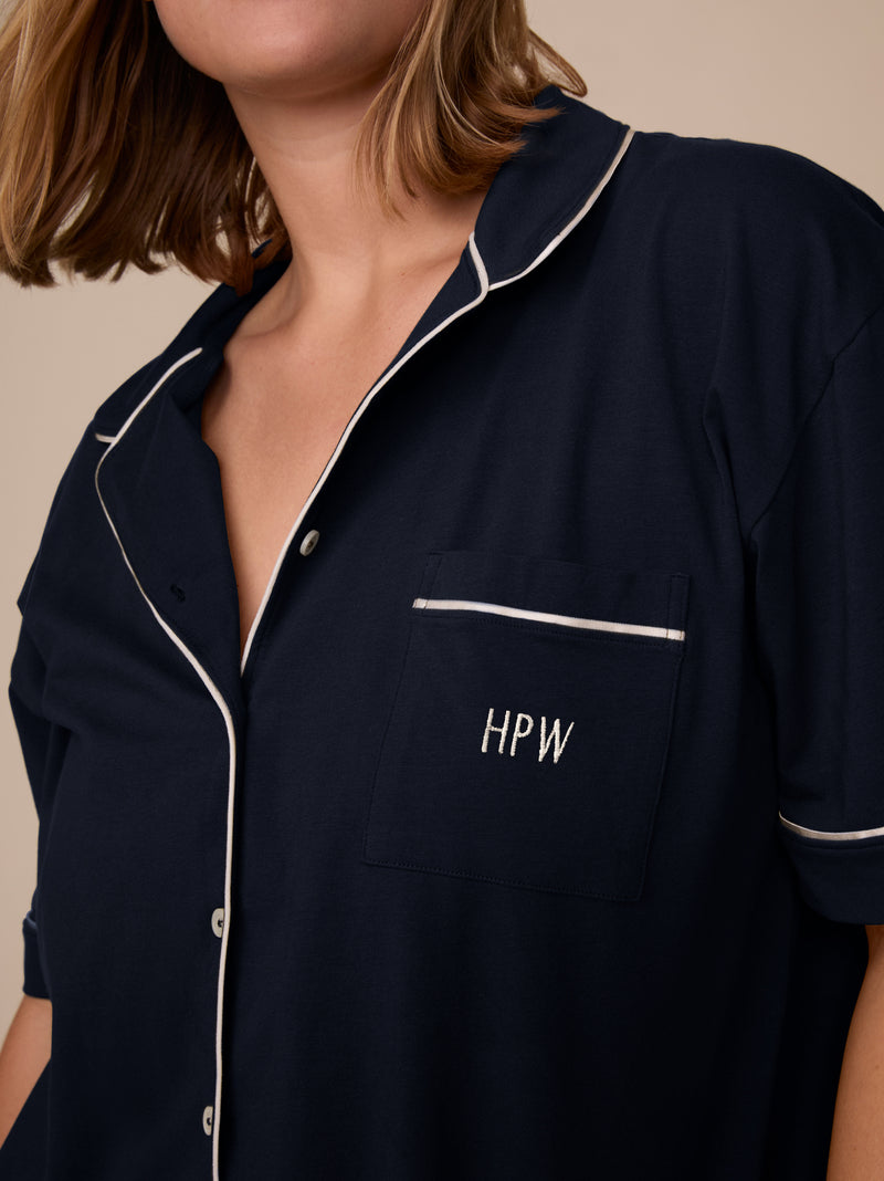 A model wears the Perfect Pima Pajama Top in Navy with “HPW” embroidered on the chest pocket in ivory thread.