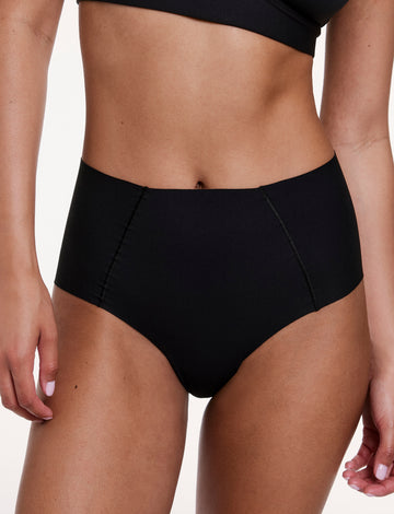 On a white studio backdrop, Courtney wears the No-Show High Waist Brief in Black, shown from the front with a high-rise silhouette and smooth, no-show fabric.
