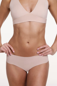 On a white studio backdrop, Gianna wears the No-Show Hiphugger in Beige, shown from the front with a mid-rise fit, wide waistband, and smooth, no-show finish. sizing: Gianna wears size Small