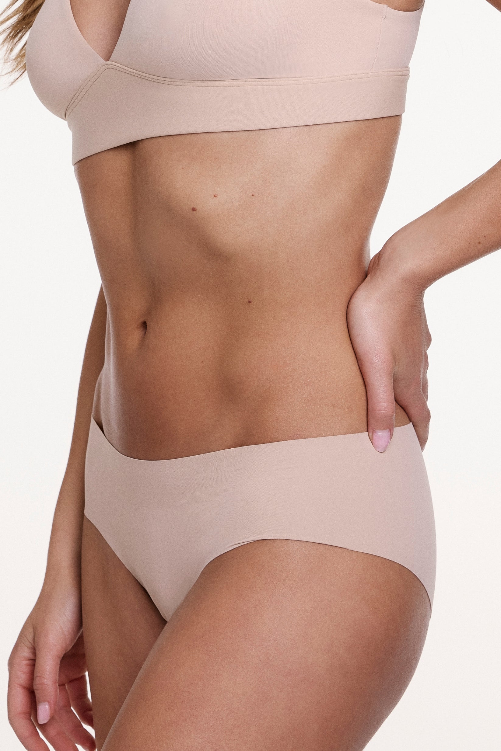 Side view of the No-Show Hiphugger in Beige, highlighting the mid-rise fit, soft stretch fabric, and seamless edges for a smooth silhouette.