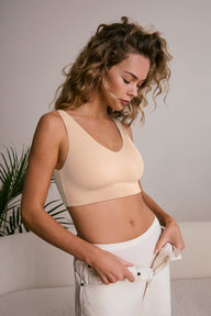 Model standing wearing the Bliss Bralette in Beige pulling on white jeans over Bliss Highwaist Briefs. sizing: Freya wears size Small