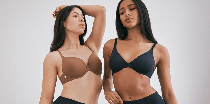 Emersyn and Ally pose confidently against a neutral backdrop, wearing Harper Wilde’s signature Base bras. Emersyn wears the Base T-Shirt Bra in Brown, offering lightly lined comfort and a smooth silhouette. Ally wears the Base Unlined Bra in Black, designed for natural shape and breathable support. Both models pair their bras with the No-Show Highwaist Brief in Black, showcasing the seamless, second-skin fit.