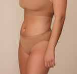 Side view of Sonnie in the Bliss Bikini in Tan. The minimal seams and comfortable leg openings are emphasized.