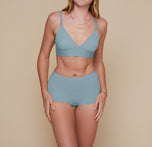 Model standing with her arms down by her sides.  She’s wearing the Bliss Triangle Bralette and matching Bliss Boyshort in the color Mist.