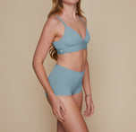 Model standing with her arms down by her sides.  She’s wearing the Bliss Triangle Bralette and matching Bliss Boyshort in the color Mist. sizing:Erin wears size Small