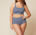 Model standing with her left hand on her hip and her right arm down by her side.  She’s wearing the Bliss Racerback Bralette and matching Bliss Boyshort in the color Steel. sizing: Summerlyn wears size Large