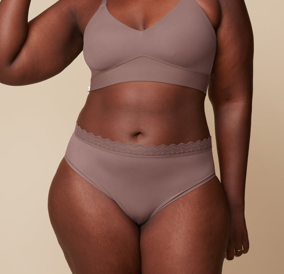 Akesha wearing the Bliss Lace Highwaist Brief and matching Bliss Lace Halterneck Bralette in Mauve. The image focuses on the lace detailing and smooth fit of both the brief and bralette. sizing: Akesha wears size XL