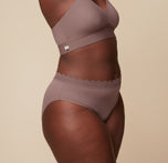 Side view of Akesha wearing the Bliss Lace Highwaist Brief in Mauve, paired with the Bliss Lace Halterneck Bralette. The image highlights the high-waisted design and comfortable, flattering fit of the brief. 