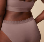 Close-up view of the Bliss Lace Highwaist Brief in Mauve on Akesha. The image focuses on the intricate lace trim and the smooth, comfortable waistband of the highwaist brief.
