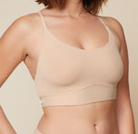 A close-up side view of Carli, focusing on her upper body. She is wearing the Bliss Racerback Bralette in Beige, showcasing the design and fit of the bralette.