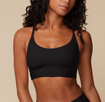 Close-up of Ally wearing the Bliss Racerback Bralette in Black, showcasing its smooth, scoop neckline and comfortable design. The soft fabric hugs the body for a comfortable fit. sizing: Ally wears size Small