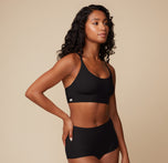 Three quarter view of Ally in the Bliss Racerback Bralette in Black. The soft microfiber fabric contours to her body for effortless comfort.