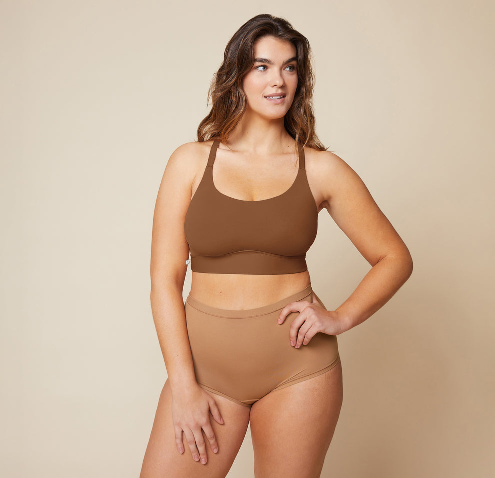 Summerlyn standing with her hand on her hip, wearing the Bliss Racerback Bralette in Brown and the Bliss Boyshort in Tan. The front view highlights the seamless, supportive fit of the bralette and the comfortable coverage of the boyshort.
