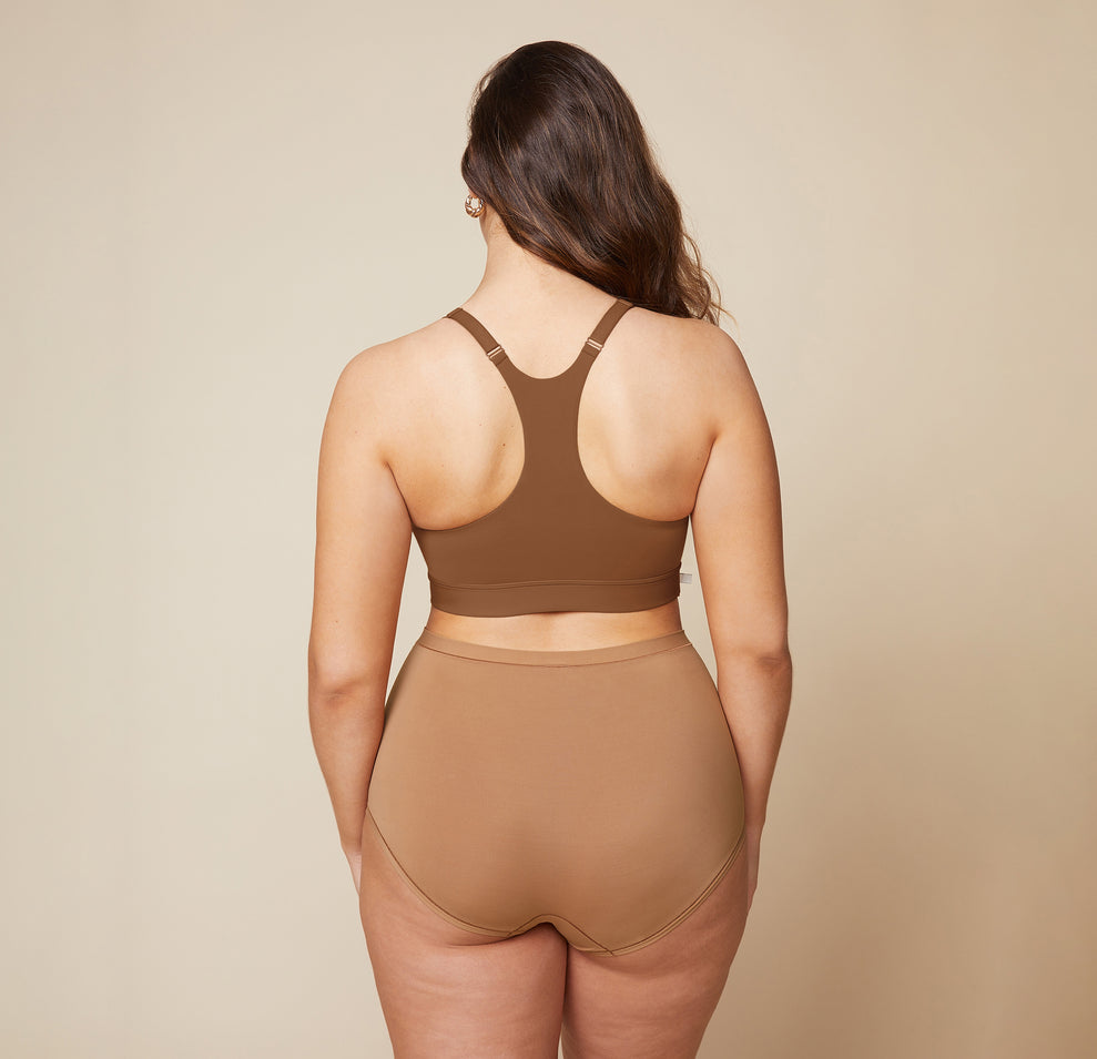 A back view of Summerlyn wearing the Bliss Racerback Bralette in Brown and the Bliss Boyshort in Tan. The image highlights the racerback design of the bralette and the full coverage provided by the boyshort.