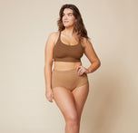 Summerlyn standing confidently with her hand on her hip, wearing the Bliss Racerback Bralette in Brown and the Bliss Boyshort in Tan. This front view showcases the full outfit, emphasizing the supportive design of both pieces.