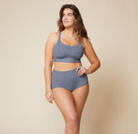 Summerlyn standing confidently with her hand on her hip, wearing the Bliss Racerback Bralette in Steel and the Bliss Boyshort in Steel. This front view showcases the full outfit, emphasizing the supportive design of both pieces.