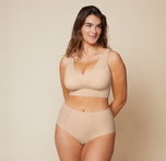 Summerlyn smiles while wearing the Bliss Sleek Lined Bralette and No-Show Highwaist Brief in Beige. The bralette features a V-neckline and seamless construction, providing smoothing and support. sizing: Summerlyn wears size Large