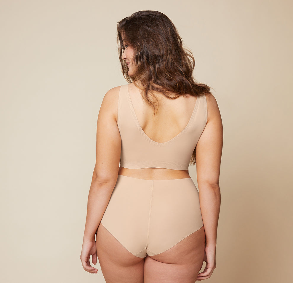 The back view of Summerlyn wearing the Bliss Sleek Lined Bralette and No-Show Highwaist Brief in Beige highlights the seamless, wireless design for a smooth, comfortable fit.
