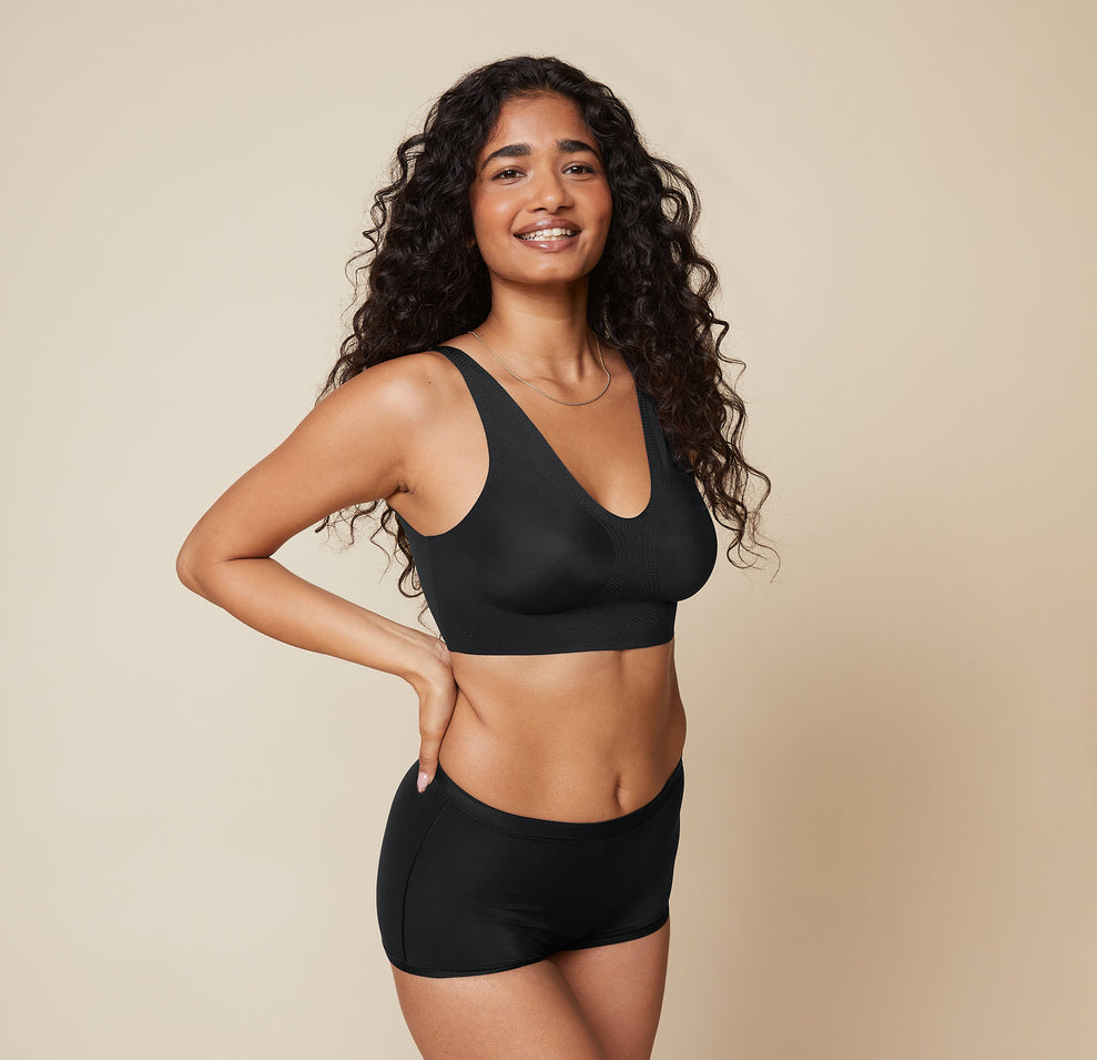 Naisha in a side view, showing the Bliss Sleek Lined Bralette and Bliss Boyshort in Black. The smooth, wireless design of the bralette is highlighted. sizing: Naisha wears size Small