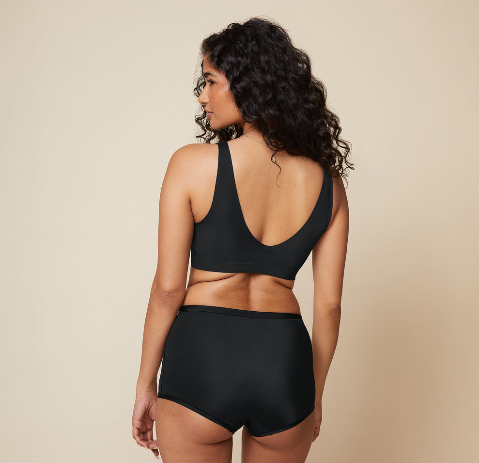 A back view of Naisha in the Bliss Sleek Lined Bralette and Bliss Boyshort in Black. The seamless construction and smooth fit of the bralette and boyshorts are shown.