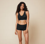 Naisha standing front-facing, wearing the Bliss Sleek Lined Bralette and Bliss Boyshort in Black. The bralette’s smooth, supportive fit and the matching boyshorts create a coordinated look.