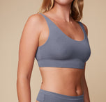 Close-up of the model's upper body, focusing on the Cloud Cotton Scoop Bralette in Slate. The image highlights the soft fabric and supportive band of the bralette.