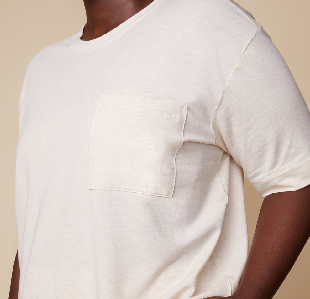 Close-up of model Akesha in the Cloud Cotton Tee in Heathered Oatmeal, showing the soft fabric and chest pocket detail. The image highlights the casual and comfortable design.