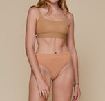 Model standing with her arms down by her sides. She’s wearing the Bliss Scoop Bralette in the color Tan and the Cloud Cotton French Cut Brief in the color Dune. sizing:Erin wears size Small