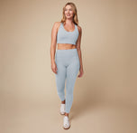 Megan styled in the Flex Convertible Sports Bra and Flex High Rise Legging in Thistle and white sneakers, walking confidently.