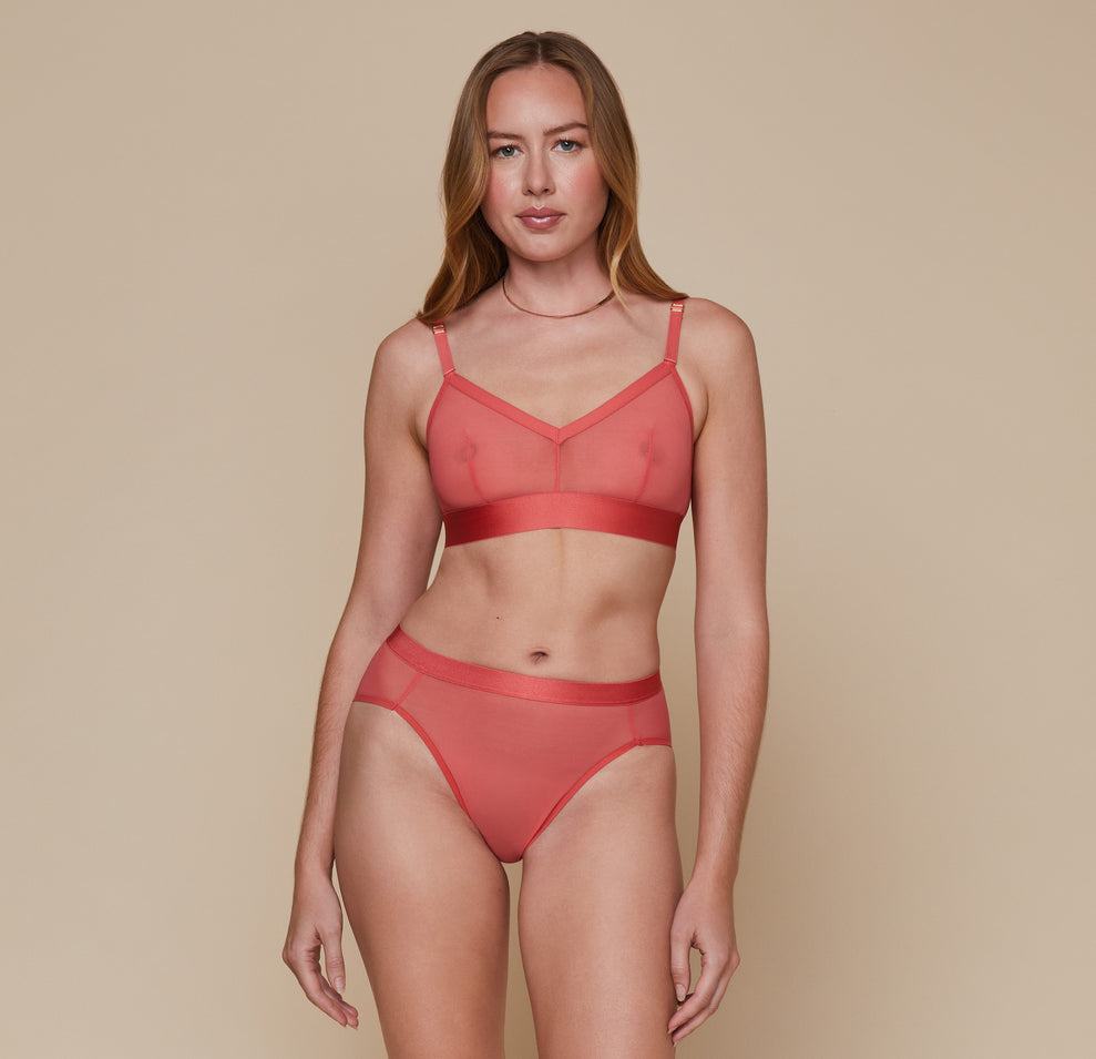 Model wearing the Luxe Mesh Bralette in the color Coral with the matching Luxe Mesh Highwaist Brief. sizing:Erin wears size Small