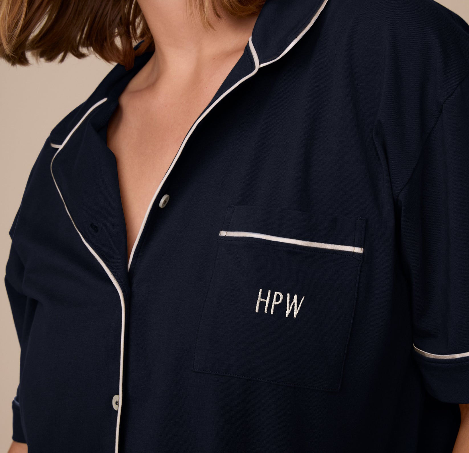 A model wears the Perfect Pima Pajama Top in Navy with “HPW” embroidered on the chest pocket in ivory thread.