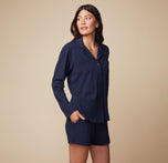 Model Anna in the Pima PJ Longsleeve and Pima PJ Shorts in Navy, standing with hands in pockets. The relaxed, comfortable fit of the loungewear is emphasized.