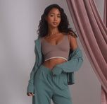 Model Ally wearing the Pima PJ Longsleeve in Rainforest, left open to reveal the Lounge Rib Triangle Bralette in Oyster. The relaxed pose emphasizes comfort and softness, highlighting the casual loungewear look.