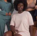 Model Akesha seated, wearing the Pima Tee in Bellini and Pima PJ Shorts, smiling and relaxed. The image highlights the soft, comfortable loungewear set.