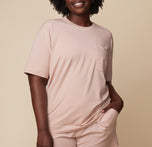 Model Akesha wearing the Pima Tee in Bellini with Pima PJ Shorts, standing in a casual pose with hands in pockets. The image emphasizes the relaxed, breathable fabric and cozy fit. sizing: Akesha wears size Large