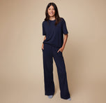 Full-length view of model Anna wearing the Pima Tee in Navy and Pima PJ Pants, standing casually. The soft, flowy fabric highlights comfort and ease.