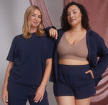 Two models, one wearing the Pima PJ Shorts and Pima Tee in Navy (Size: Large), and the other in the Pima PJ Shorts paired with the Bliss Lace Bralette in Mauve. The image highlights the versatility and comfort of the PJ set.