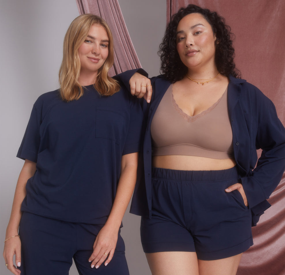 Two models, one wearing the Pima PJ Shorts and Pima Tee in Navy (Size: Large), and the other in the Pima PJ Shorts paired with the Bliss Lace Bralette in Mauve. The image highlights the versatility and comfort of the PJ set.