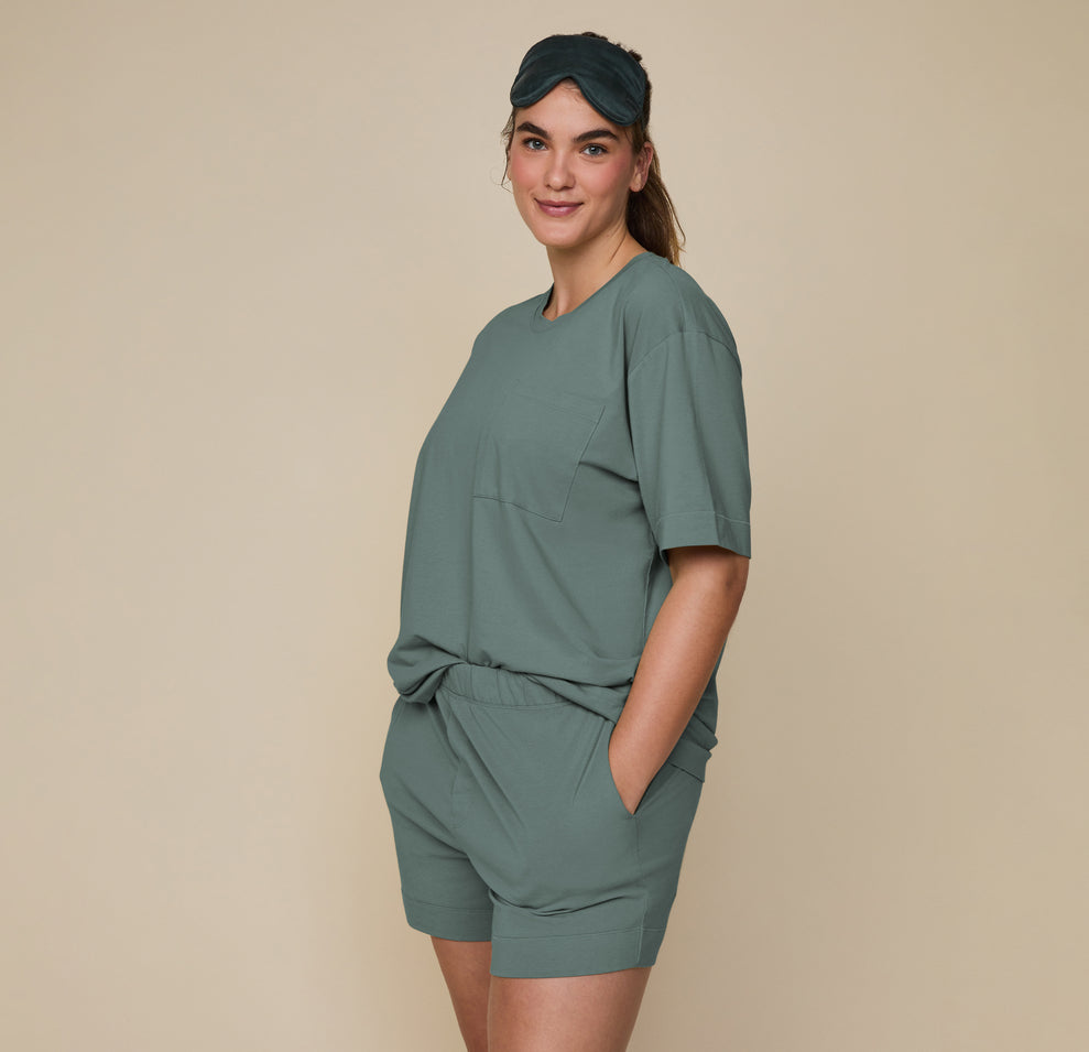 Side view of model Summerlyn wearing the Pima Tee in Rainforest with Pima PJ Shorts, standing casually with hands in pockets. The comfortable and easy fit is highlighted.