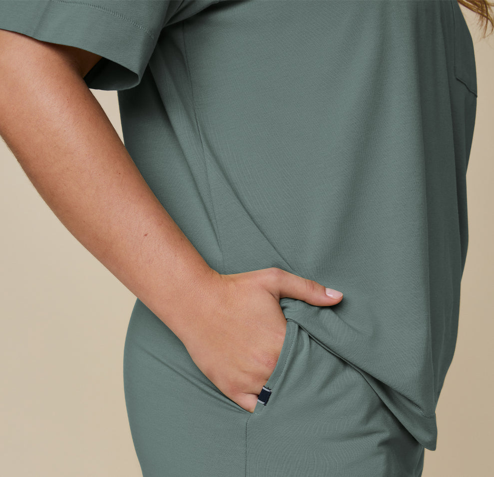 Close-up of model Summerlyn wearing the Pima Tee in Rainforest, with her hand in the pocket of the Pima PJ Shorts. The image highlights the soft, breathable fabric and casual fit.
