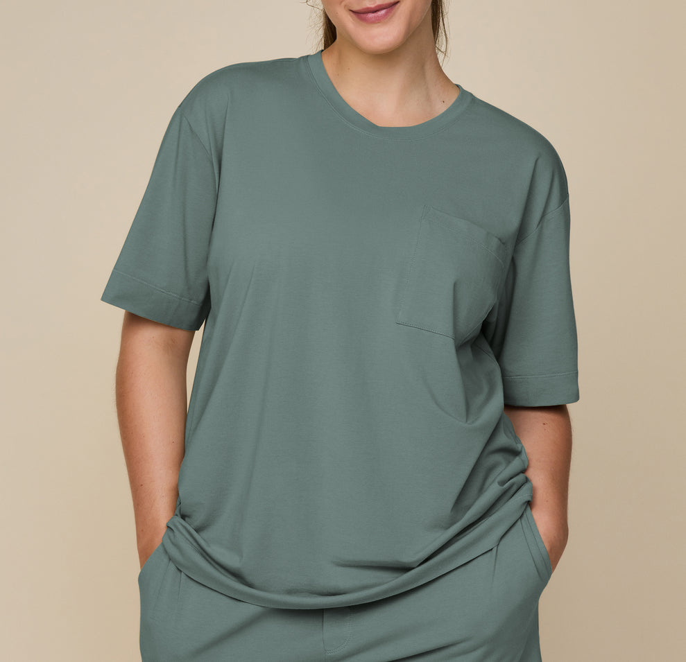 Close-up of model Summerlyn in the Pima Tee and Shorts in Rainforest, with hands in pockets, emphasizing the soft, flowy fabric and relaxed fit. sizing: Summerlyn wears size Large