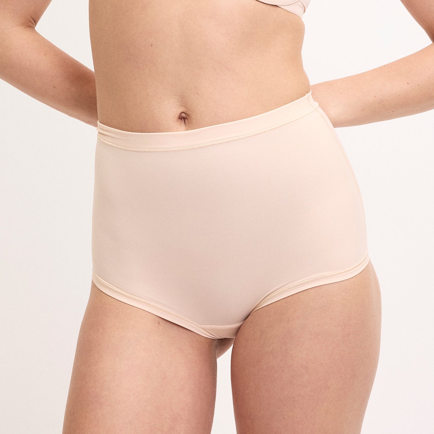 On a white studio backdrop, Megan wears the Bliss Boyshort in Rose, featuring a smooth high-rise silhouette with soft microfiber fabric and full coverage through the hips and back.