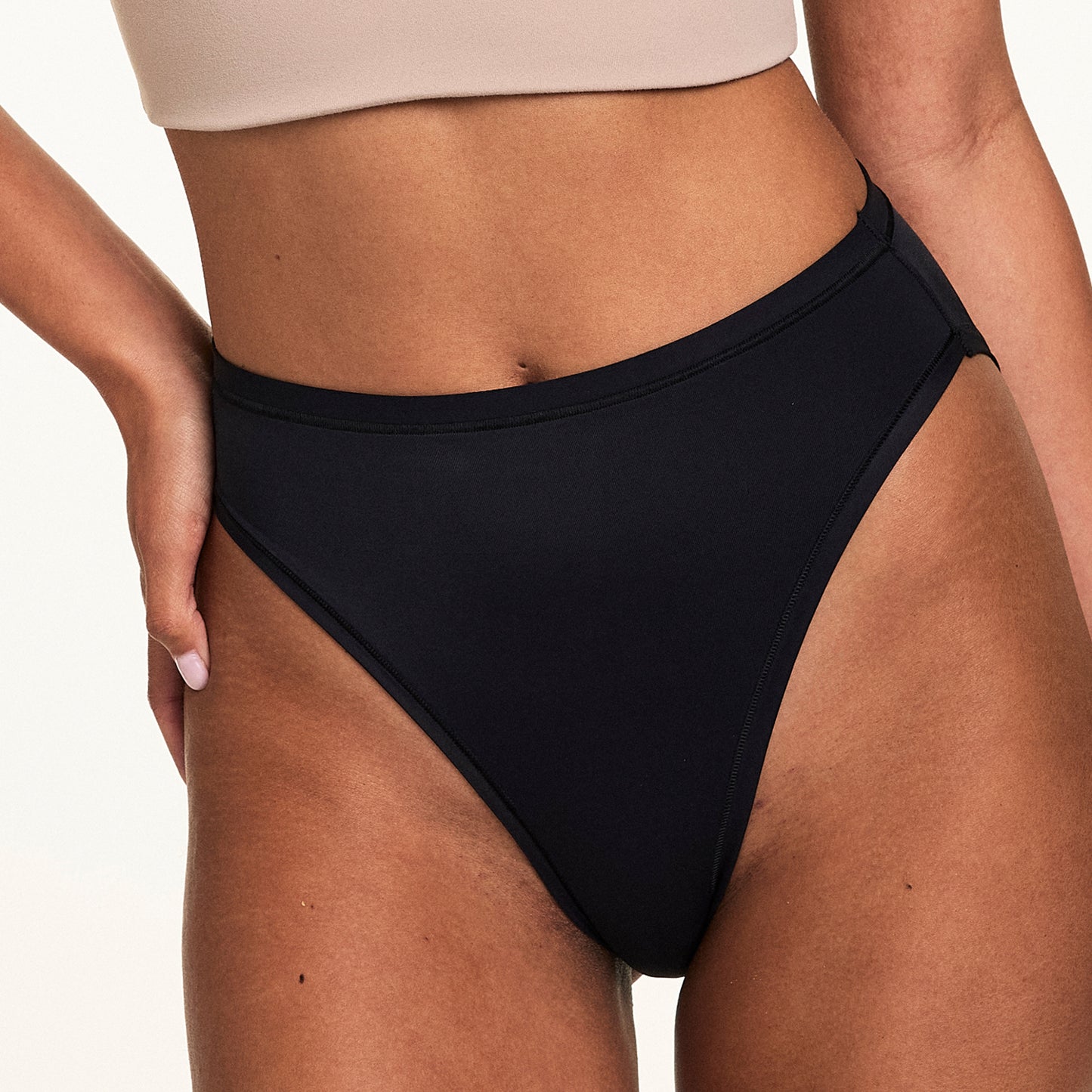 Close-up on a light studio backdrop of Courtney wearing the Bliss French Cut in Black. The underwear features a high-cut leg, smooth waistband, and soft fabric for everyday comfort.