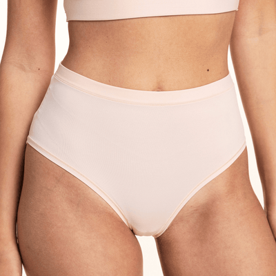 In a studio setting, Laura wears the Bliss Lace Highwaist Brief in Rose, highlighting the high-rise silhouette, smooth microfiber fabric, and clean edge waistband.